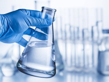 Laboratuvar kabı plastik eldiven analist'ın elinde.
