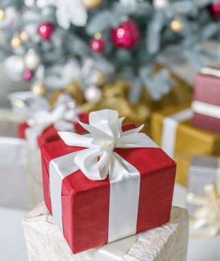 Kırmızı hediye kutusu ve arka planda bir şekilde dekore edilmiş yeni yıl ağacı. 