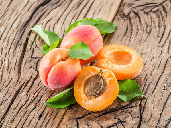 Apricots and its cross-section on the old wooden table. — Stock Photo, Image