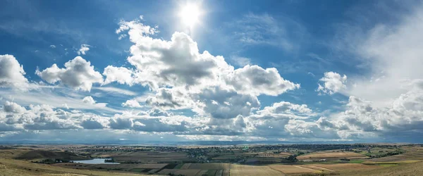 Alanları ve köyleri üzerinde bulutlu gökyüzü güneş ışınları. — Stok fotoğraf