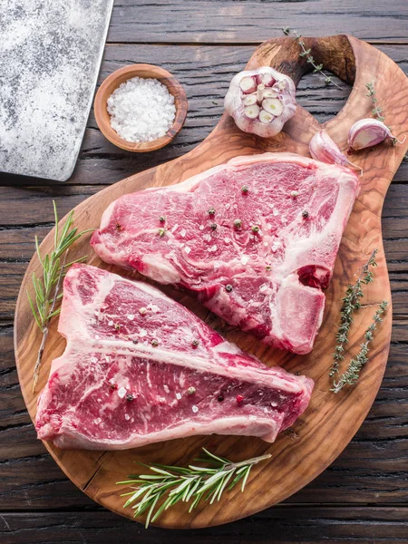 Bife T-bone com especiarias na placa de corte de madeira . — Fotografia de Stock