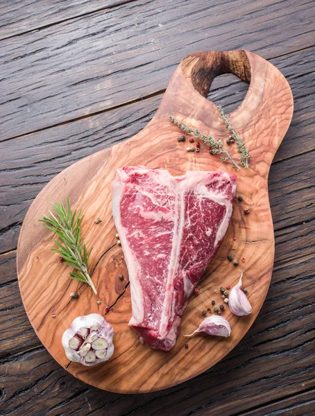 Steak T-bone with spices on the wooden cutting board. — Stock Photo, Image