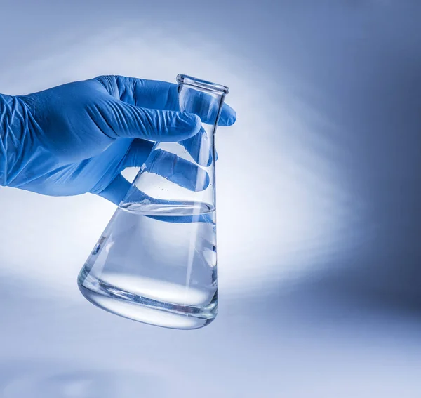 Laboratory beaker in analyst's hand in plastic glove. — Stock Photo, Image