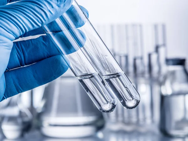 Laboratuvar kadehler analist'ın elinde plastik eldiven.