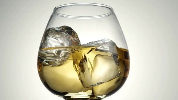 Glas mit Whiskey und Eiswürfeln dreht sich um die eigene Achse. — Stockvideo