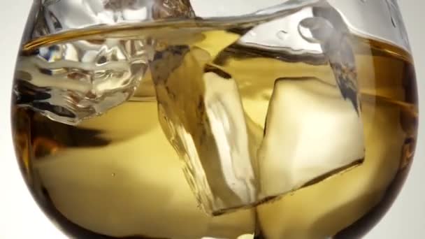 Verre avec whisky et glaçons tourne par axe .