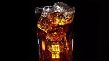 Kola ve buz ile cam siyah bir zemin üzerine kendi ekseni etrafında döndürün. 4k video.