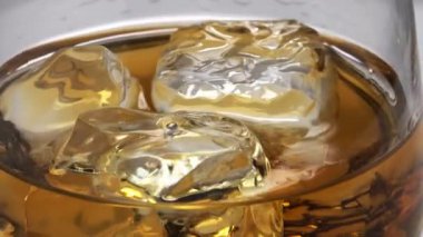 Buzlu cam içine viski döktü. Cam döner. 4k video.