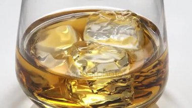 Buzlu cam içine viski döktü. Cam döner. 4k video.