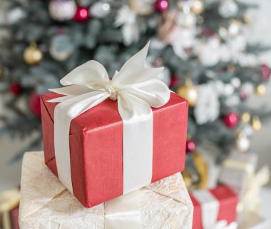 Kırmızı hediye kutusu ve arka planda bir şekilde dekore edilmiş yeni yıl ağacı. 