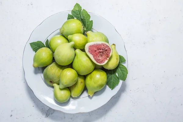 Talerz pełen owoców dojrzałych fig na stary stół kuchenny. — Zdjęcie stockowe