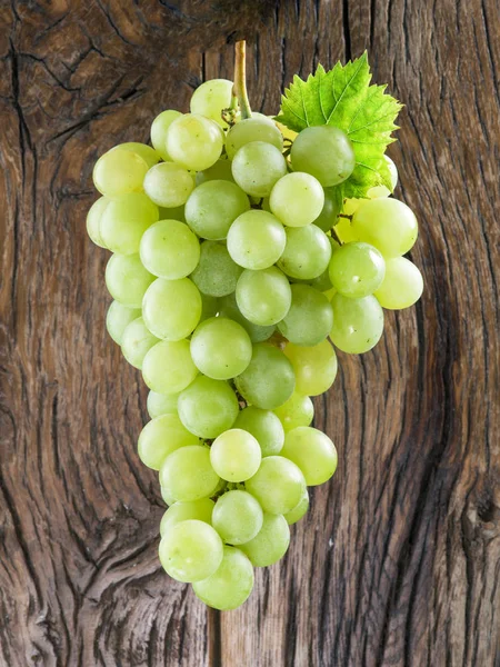 Um bando de uvas brancas. Madeira velha no fundo . — Fotografia de Stock