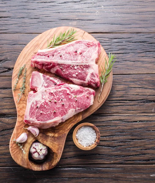 Filete T-bone con especias en la tabla de cortar de madera . — Foto de Stock