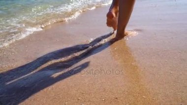 Kadın ayak kumlu sahilde dalgaların gidin. Ağır çekim 100 fps.