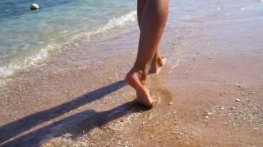 Kadın ayak kumlu sahilde dalgaların gidin. Ağır çekim 100 fps.