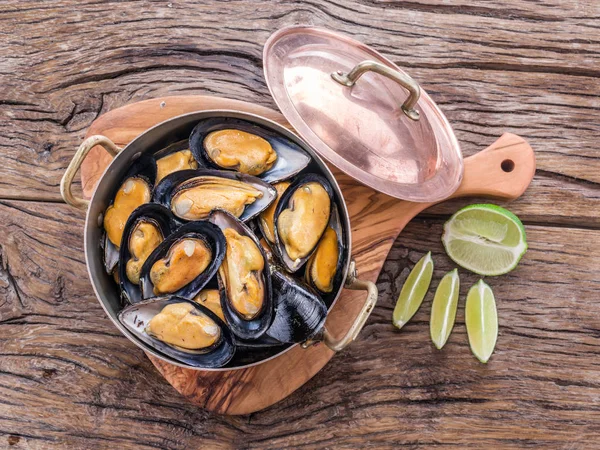 Moules dans une casserole en cuivre sur la table en bois . — Photo