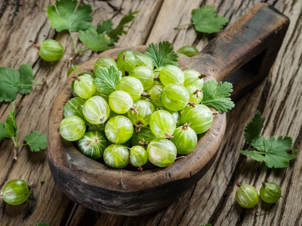 Gooseberries in the wooden bowl on the table. — Stock Photo, Image