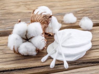 Fluffy cotton ball and cotton swabs and pads on wooden table. clipart