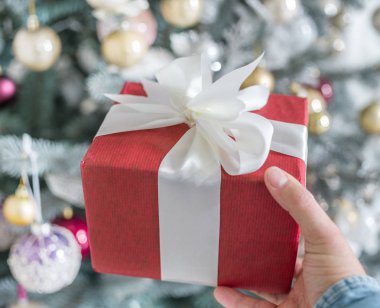 Kırmızı hediye kutusu ve arka planda bir şekilde dekore edilmiş yeni yıl ağacı. 