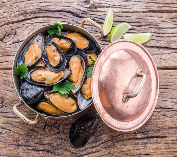 Moules dans une casserole en cuivre sur la table en bois . — Photo