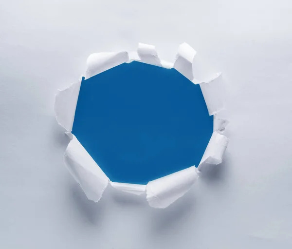 Lyuk-egy papírra. Kék háttér a lyukba. — Stock Fotó