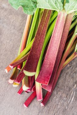 Edible rhubarb stalks on the wooden table.  clipart
