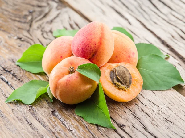 Apricots and its cross-section on the old wooden table. — Stock Photo, Image