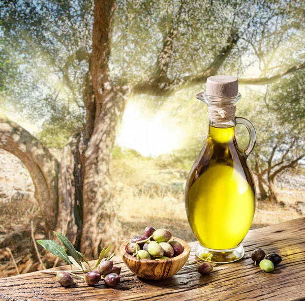 Bayas de oliva en el cuenco de madera y botella de aceite de oliva en el —  Fotos de Stock