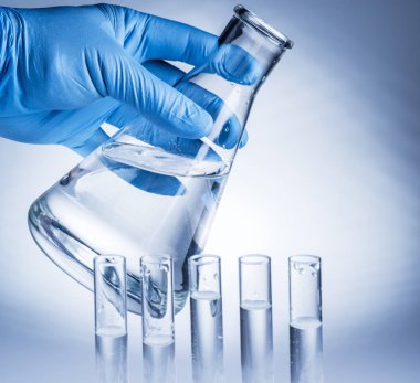 Laboratuvar kabı plastik eldiven analist'ın elinde.