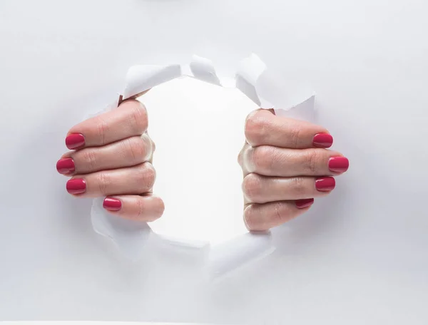 Woman's hands tearing the hole on a paper.