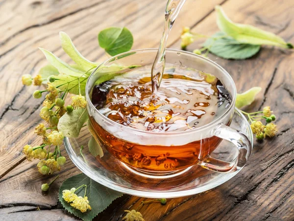 Tasse Lindentee und Lindenblüten auf dem Holztisch. — Stockfoto