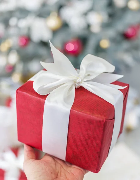 Rote Geschenkbox und geschmückter Neujahrsbaum auf dem Hintergrund. — Stockfoto