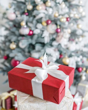 Kırmızı hediye kutusu ve arka planda bir şekilde dekore edilmiş yeni yıl ağacı. 