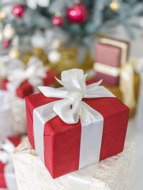 Kırmızı hediye kutusu ve arka planda bir şekilde dekore edilmiş yeni yıl ağacı. 