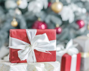 Kırmızı hediye kutusu ve arka planda bir şekilde dekore edilmiş yeni yıl ağacı. 