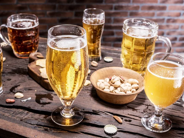 Copos de cerveja e lanches na mesa de madeira . — Fotografia de Stock