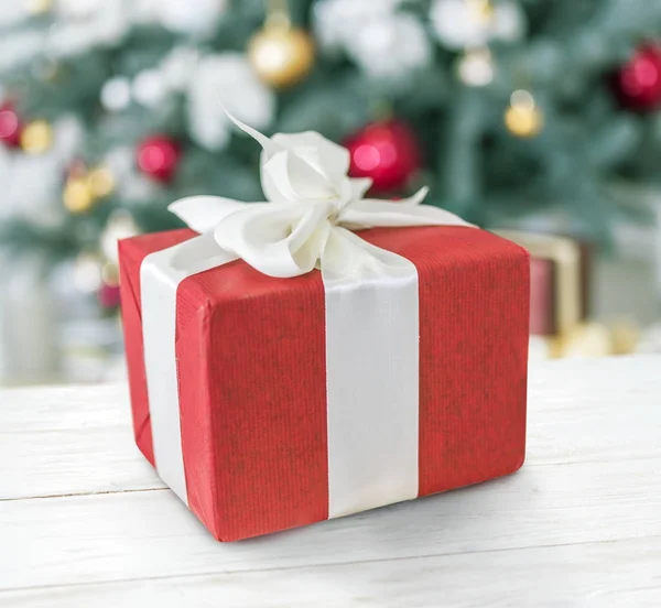 Caja de regalo roja y árbol de Año Nuevo decorado en el fondo . — Foto de Stock