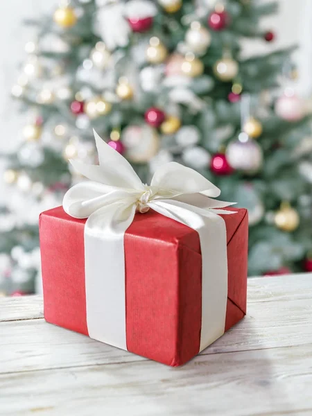 Caja de regalo roja y árbol de Año Nuevo decorado en el fondo . — Foto de Stock