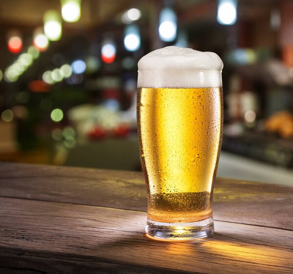 Frosty glass of light beer on the bar counter.