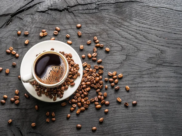 Kopp kaffe omgiven av kaffebönor. Ovanifrån. — Stockfoto