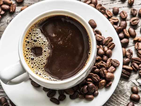 コーヒー豆に囲まれたコーヒー カップ。トップ ビュー. — ストック写真