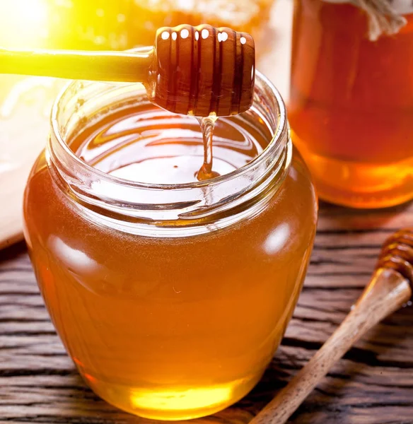 Miel goteando de un cazo en el frasco lleno de miel fresca . —  Fotos de Stock