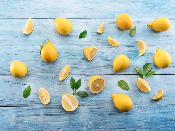 Limoni maturi e foglie di limone su sfondo blu di legno. Vista dall'alto — Foto Stock