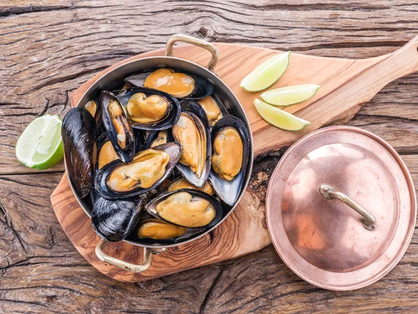 Mussels in copper pan on the wooden table. — Stock Photo, Image