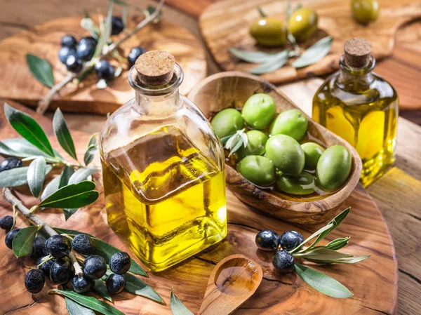 Aceite de oliva y bayas están en la bandeja de madera de oliva . —  Fotos de Stock