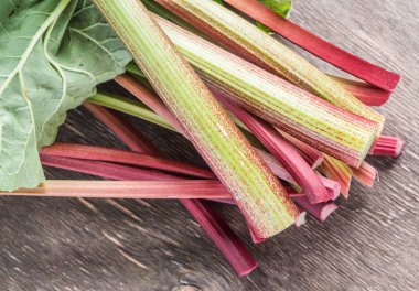 Edible rhubarb stalks on the wooden table.  clipart