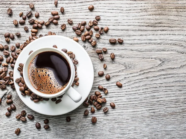 Kopp kaffe omgiven av kaffebönor. Ovanifrån. — Stockfoto