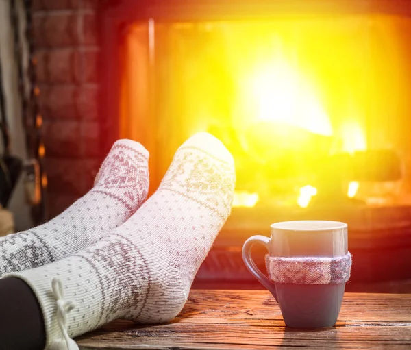 Aquecimento e relaxamento perto da lareira com uma xícara de bebida quente . — Fotografia de Stock