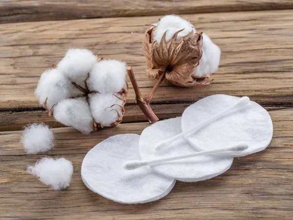 Fluffy cotton ball and cotton swabs and pads on wooden table.