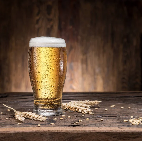 Frosted glass of beer on the wooden table.